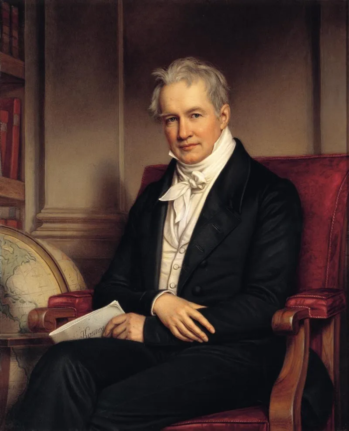 Painting of Alexander von Humboldt seated in a red upholstered chair, wearing a black coat and white cravat, holding a paper beside a globe and bookshelves in a study.
